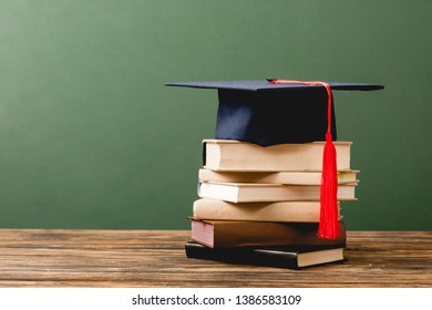 Books And Academic Cap On Wooden Surface Isolated On Green