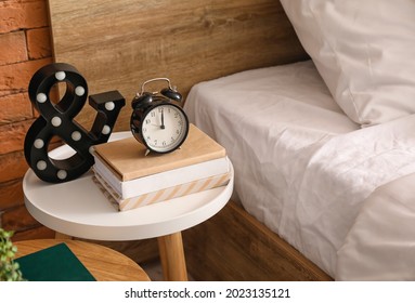 Books, Alarm Clock And Decor On Bedside Table