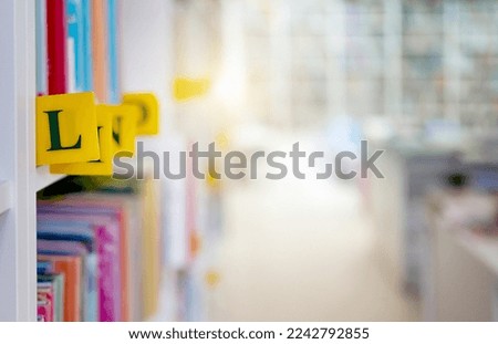 Books with alphabet letters classification in library with blurred background. Biblioteque shelfs in univercity