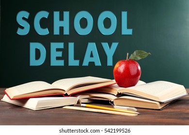 Books And Apple On Chalkboard Background With Text SCHOOL DELAY 