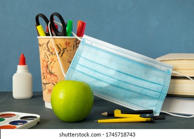 Books, Apple And Stationery To Study At School. The Medical Mask As A Symbol Of Covid-19. Back To School, Protection From Infection Is A Concept. Horizontal Orientation. Selective Focus.