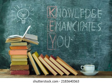 books and blackboard with drawing of a lightbulb and slogan knowledge emancipates you,learning,education,back to school concept