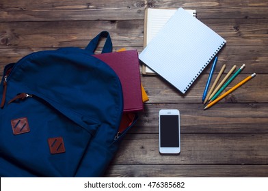 Books , Blue Backpack , Stationery For Study On A Wooden Background. Mobile Phone.