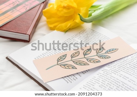Books with bookmarks and flower on bed, closeup