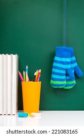 Books , Colored Pencil In Yellow Glass And Winter Gloves On Green Chalkboard. / End Of School. Winter Break