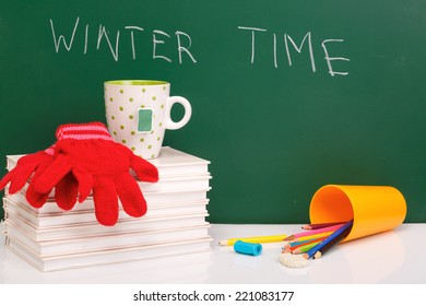 Books , Colored Pencil In Yellow Glass And Winter Gloves On Green Chalkboard. / End Of School. Winter Break