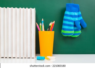 Books , Colored Pencil In Yellow Glass And Winter Gloves On Green Chalkboard. / End Of School. Winter Break