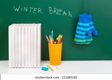 Books , Colored Pencil In Yellow Glass And Winter Gloves On Green Chalkboard. / End Of School. Winter Break