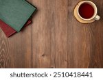 Books with cup of tea on wooden background from above. Flat lay, top view. Copy space