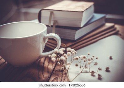 Books, flowers, white cup and opened diary on wooden table - Powered by Shutterstock