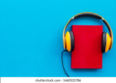 Books With Headphones For Listening To Audiobook On Blue Background Top View Copy Space