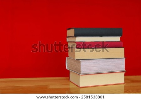 books and books on red wooden shelf, stack of books on table against red background. space for text, red book, pile of colorful books on wooden table