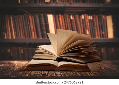 Books on wooden table against full shelves in library