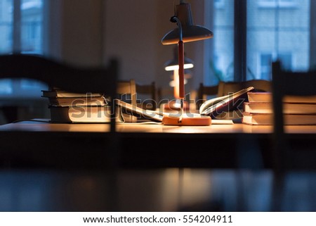 Books on wooden table under lamp light