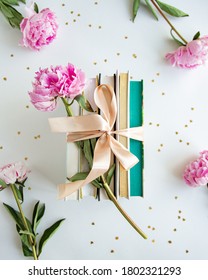 Books with peonies on a table