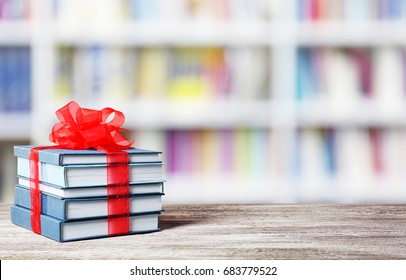 Books with ribbon bow as gift on wooden table at library