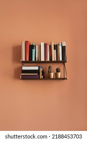 Books stack on hanging shelf. Coral peach wall background. Aesthetic minimal interior design. Reading, education concept with bookshelf