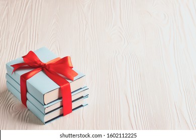 Books tied with ribbon on a wooden background with copy space: concept of donating books.