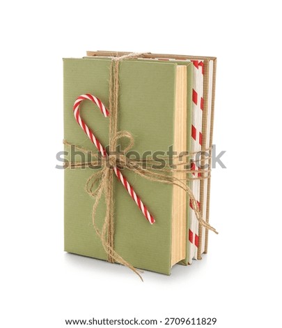 Books tied with string and candy cane on white background. Christmas celebration