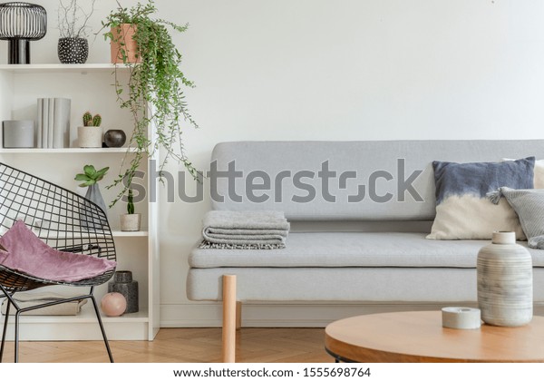 Bookshelf with knick knacks next to comfortable grey\
sofa in chic living\
room