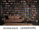 Bookshelves in the library. Large bookcase with lots of books. Sofa in the room for reading books. Library or shop with bookcases. Cozy book background. Bookish, bookstore, bookshop. 