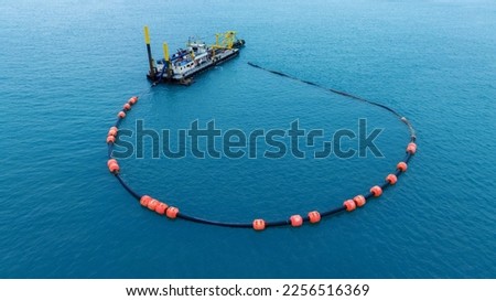 Boom floating barrier used to contain an oil spill. An offshore vessel performing oil spill response exercise in the sea.