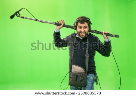 Boom microphone operator testing sound at TV studio on green key chroma background. High quality photo