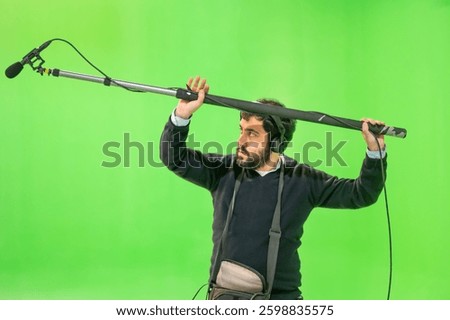 Boom microphone operator testing sound at TV studio on green key chroma background. High quality photo