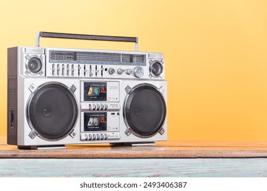 Boombox radio stereo cassette recorder on vintage wooden shelf front yellow background. Retro old style filtered photo