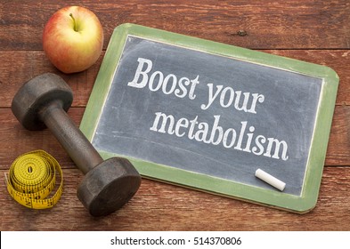 Boost your metabolism concept -  slate blackboard sign against weathered red painted barn wood with a dumbbell, apple and tape measure
