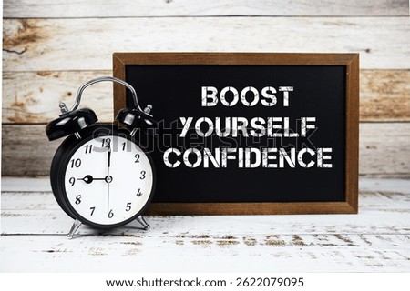 Boost Yourself Confidence text message and alarm clock on wooden background
