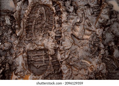 A Boot Print In The Mud Close-up. Footprint In The Dirt. Bottom Of Shoes.