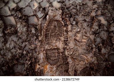 A boot print in the mud close-up. Footprint in the dirt. Bottom of shoes.