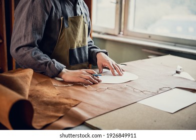 In the boot shop, an experienced shoemaker starts the process of producing shoes, makes a pattern on the skin. - Powered by Shutterstock