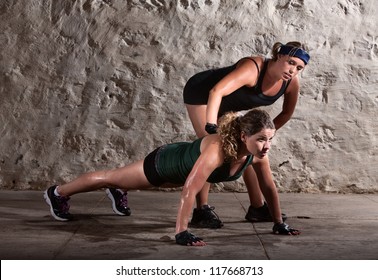 Bootcamp workout coach helps woman with push ups - Powered by Shutterstock