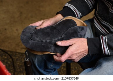 Bootmaker Making Shoes Sitting In Workshop. Shoemaker Holding Gray Suede Shoe In Hands Before Stitching. Bespoke Handmade Shoes