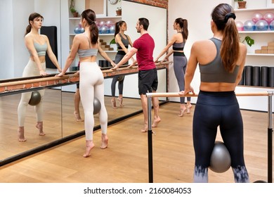 Booty Barre Fitness Class Standing Near Barre With Balls And Performing Releve Exercise In Spacious Studio With Mirror. Fitness Class Concept.