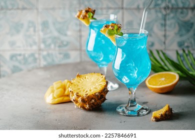 Boozy Blue Hawaii Cocktail with Rum and Pineapple on gray background