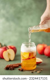 Boozy Refresing Cold Hard Apple Cider in a Pint Glass and Bottle on wooden table. Copy space