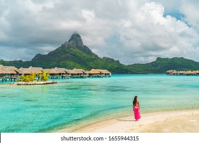 Bora Bora luxury resort honeymoon vacation destination in Tahiti, French Polynesia. Woman walking on idyllic beach landscape.