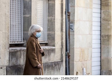 BORDEAUX, FRANCE - FEBRUARY 24 2022: Selective Blur On Old Woman With Facemask, Standing In A Street Of Bordeaux During The Coronavirus Covid 19 Health Crisis.



