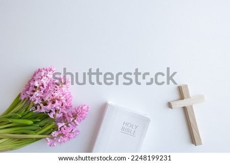Border of closed bible, cross and bouquet of pink hyacinth flowers on a white background with copy space