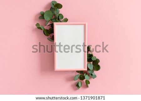Border frame made of eucalyptus branches and photo frame mockup on a pink background