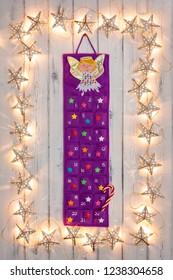 A Border Of Golden Star Christmas Lights, With A Advent Calander And Candy Stick In The Middle, On A Destressed Woodern Background