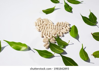 Border made of green leaves and pills. The capsules are laid out in the shape of a heart. Alternative and Nutraceutical Medicine Topics.