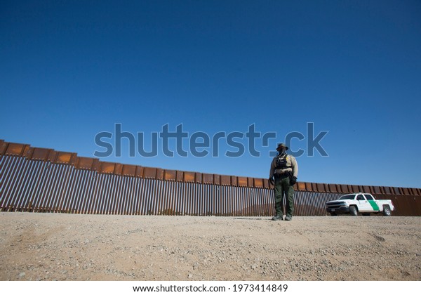 A Border\
Patrol agent stands by the wall separating the United States and\
Mexico on May 12, 2021 in Yuma,\
Arizona.