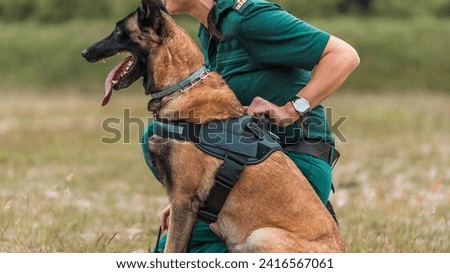 Border Patrol Officer with Trained Belgian Malinois on Duty in Open Field - A Showcase of Security and Loyalty in Law Enforcement