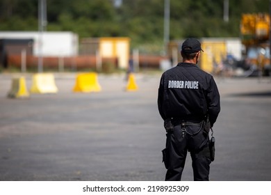 Border police officer is seen from the back guarding the a border. - Shutterstock ID 2198925309