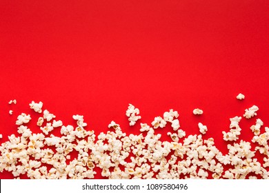 Border of popcorn scattered over red background with copy space, top view. Minimalistic design for movie poster, entertainment concept
