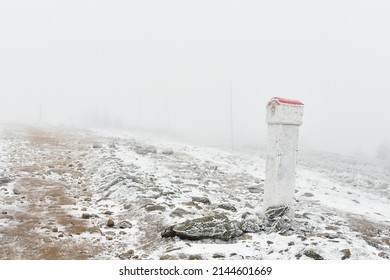 Border post along the border of Poland Czech Republic on a mountain hiking trail, frosty landscape on a foggy winter day.